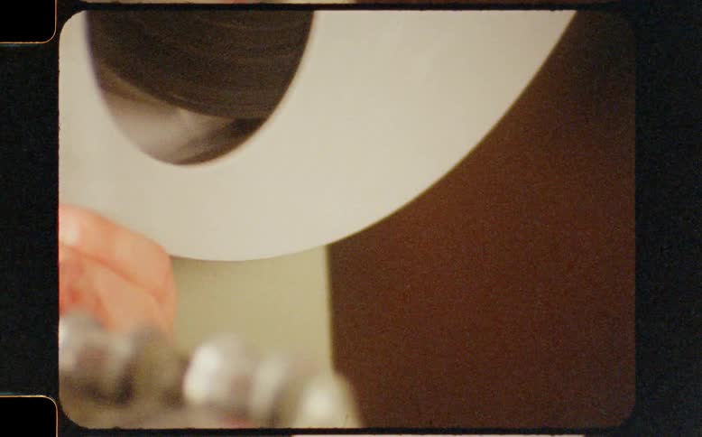 Authentic super 8 film captures a close-up detail of a spinning reel on a vintage tape player