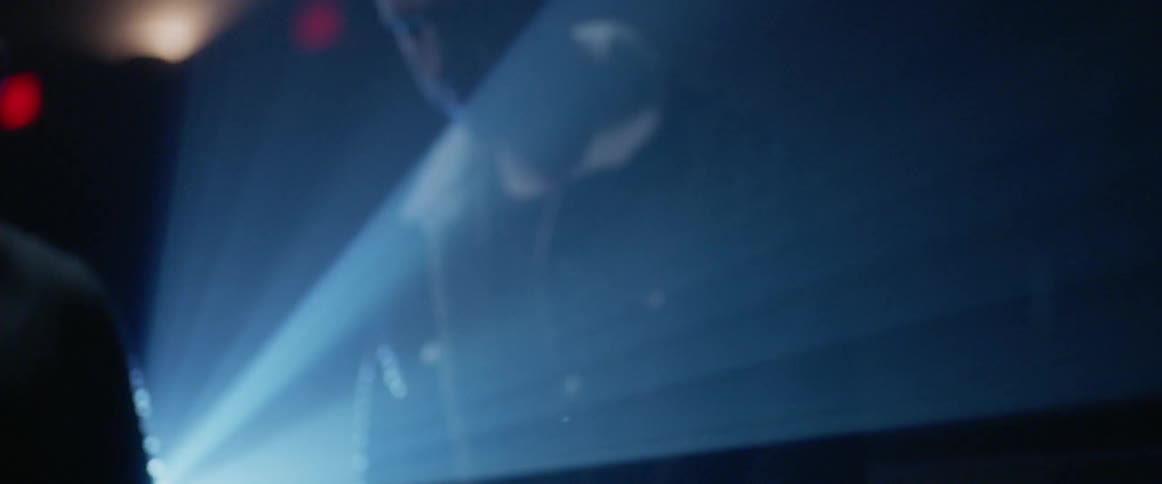 A man walks onto a stage in front of a light