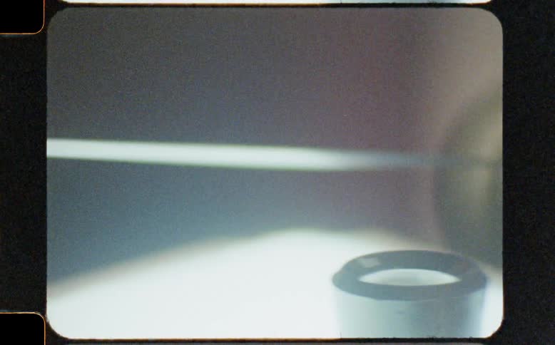 Vintage 8mm film captures the abstract details of levers and rollers on industrial machinery in motion