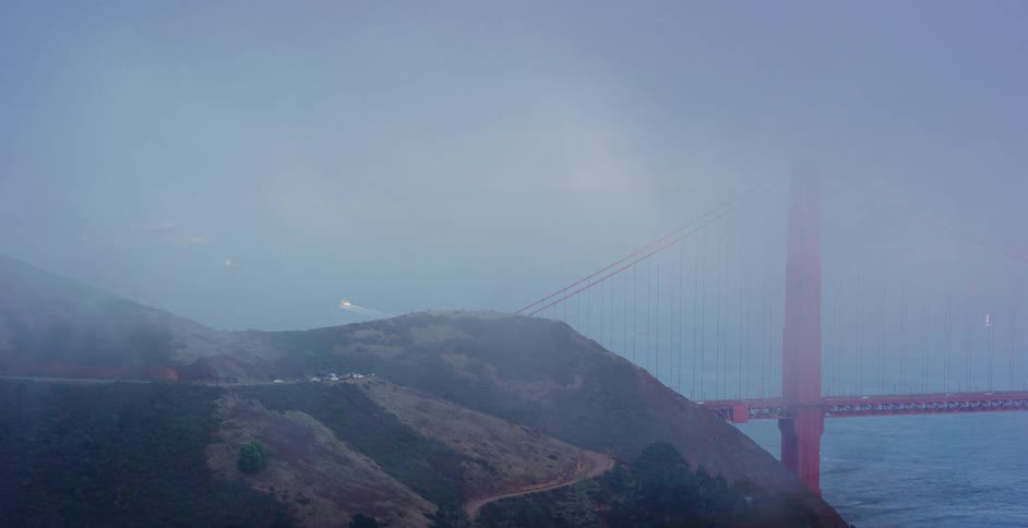 A cinematic parallax view of the Golden Gate Bridge in San Francisco, shrouded in thick fog at dusk