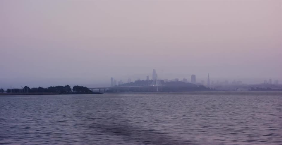 A hazy, atmospheric view of the distant San Francisco skyline and Bay Bridge across the bay