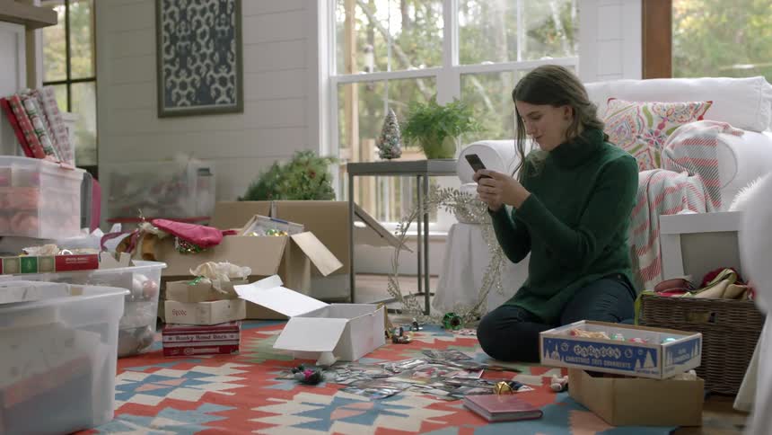 A woman sitting in a living room is texting on a cellphone