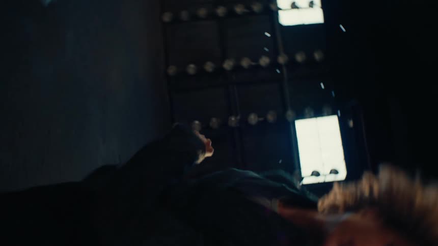 A dancer with voluminous blonde hair performs a surreal, gravity-defying slow-motion dance in a cavernous, sun-drenched industrial warehouse