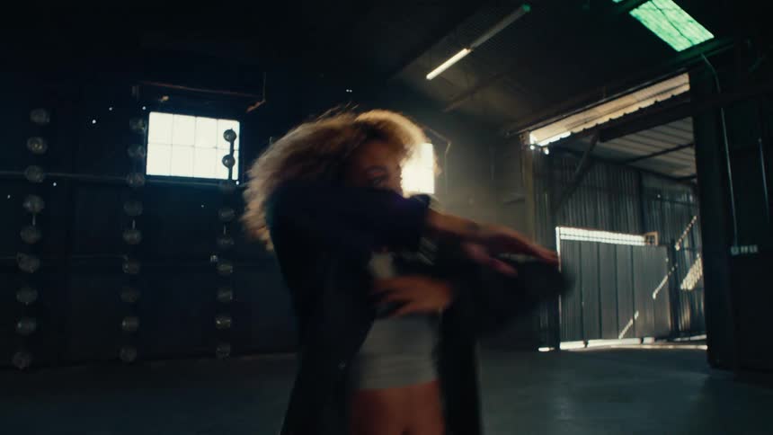 Slow motion shot of a talented female dancer performing a passionate contemporary routine in an empty, backlit warehouse