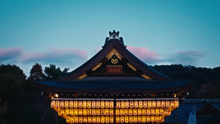 A traditional Japanese temple with rows of glowing paper lanterns stands against a beautiful dusk sky
