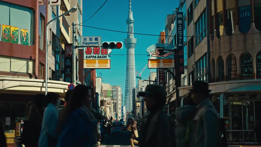 The iconic Tokyo Skytree is framed by a bustling city street as silhouetted pedestrians and traffic pass by