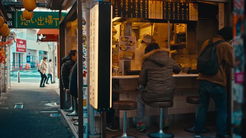 Customers eat at a small, traditional food stall in an alleyway in Tokyo, Japan, as people walk by on the street