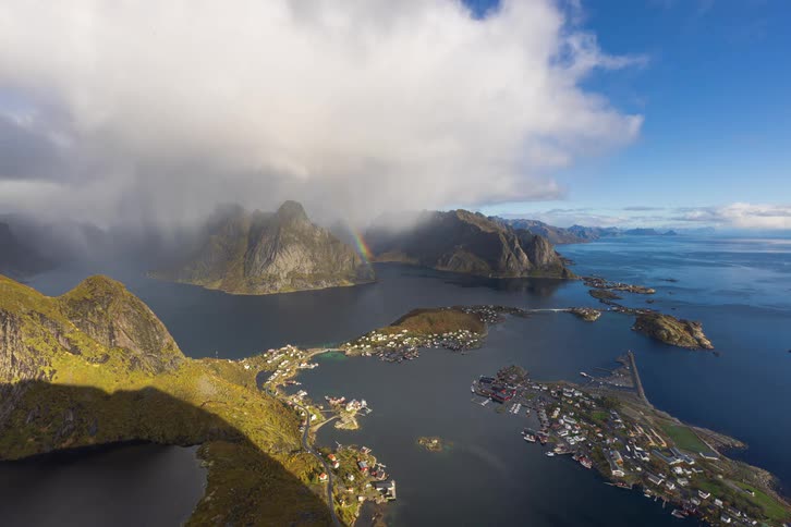 A stunning aerial timelapse of the Lofoten Islands in Norway shows sun and clouds moving across the mountains and sea as a beautiful rainbow appears