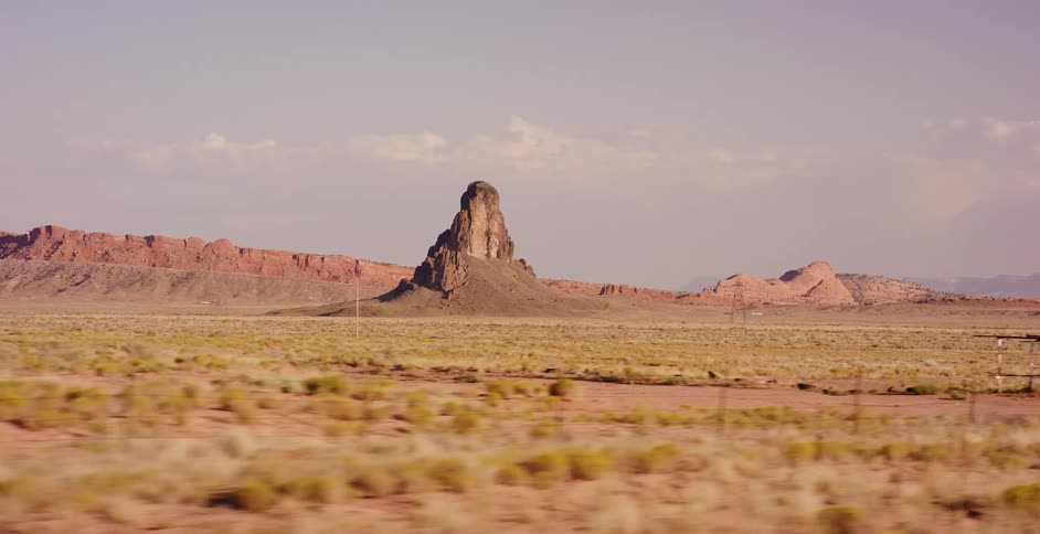 Driving through the vast desert landscape of the American Southwest, passing a prominent butte rock formation