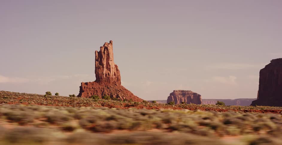 A scenic drive past the iconic red rock buttes of Monument Valley, captured from a moving vehicle