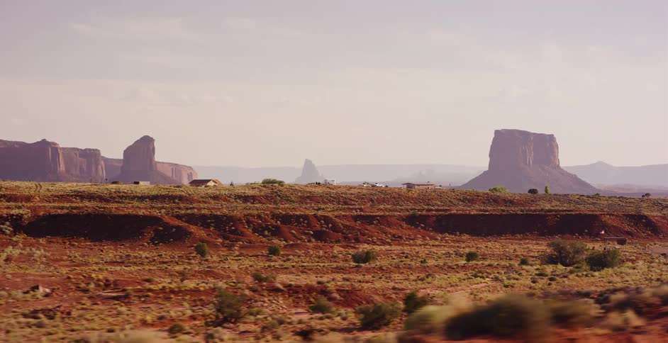 A smooth, cinematic tracking shot from a moving vehicle reveals the vast, iconic desert landscape of Monument Valley
