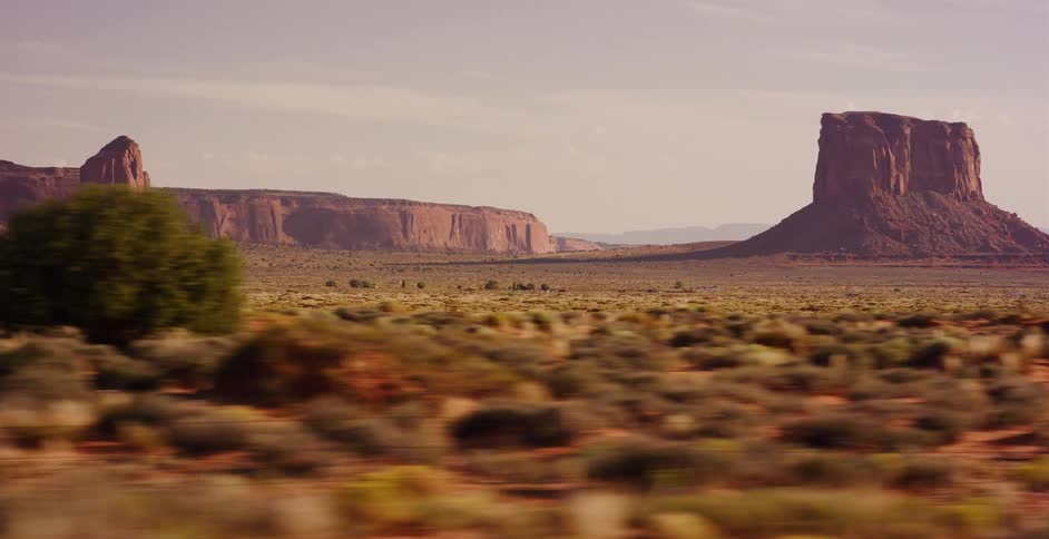 A fast-moving vehicle's perspective captures the iconic red buttes and vast desert landscape of Monument Valley