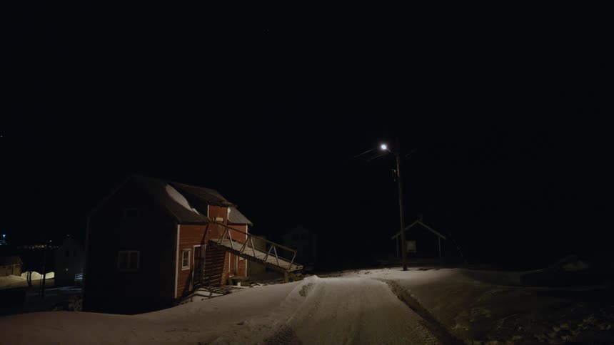 A street lamp flickers and goes out, leaving a red house on a snowy road in complete darkness on a cold winter night