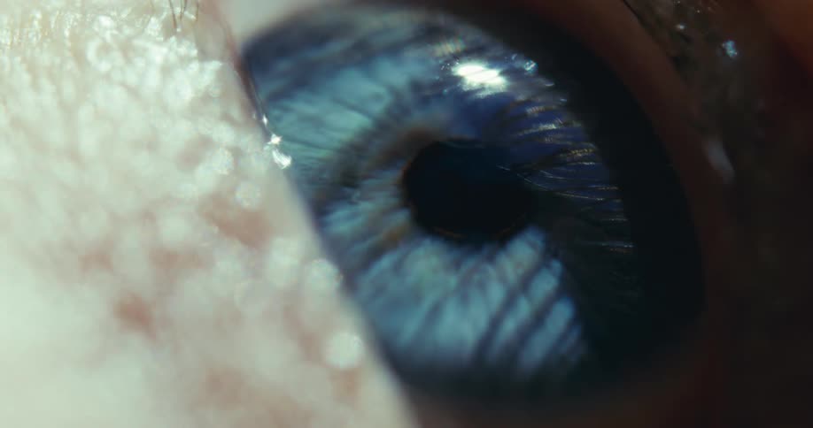 An extreme close-up macro shot slowly focuses on the detailed iris of a blue human eye