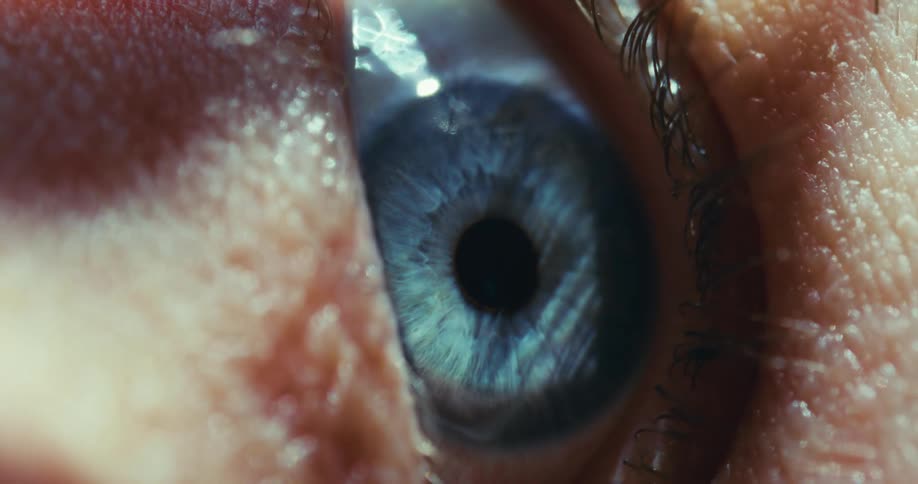 A dramatic macro shot of a blue human eye slowly closing and then reopening