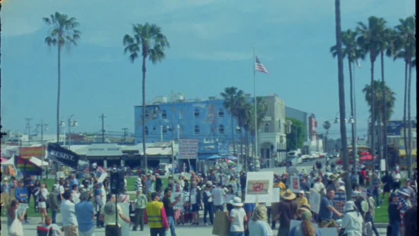 Vintage 16mm footage captures a large political demonstration taking place on a sunny day at Venice Beach, California