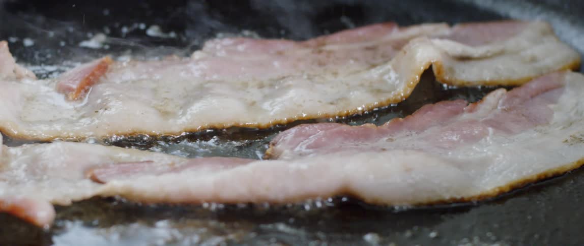 Bacon sizzling and cooking in a pan