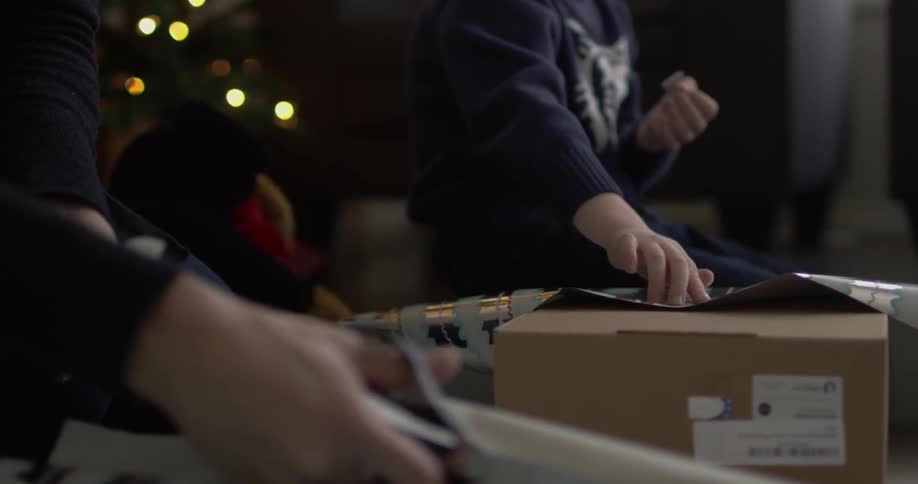 A boy helps wrap some gifts