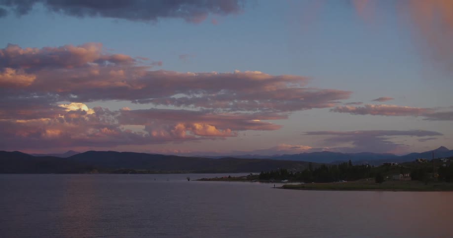 A beautiful, serene sunset with pink clouds over a calm mountain lake