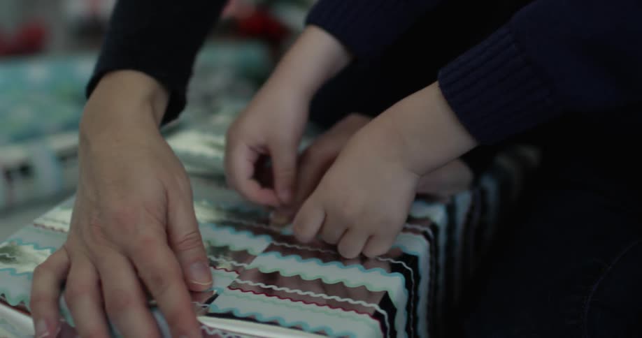 A woman and child wrap a christmas gift