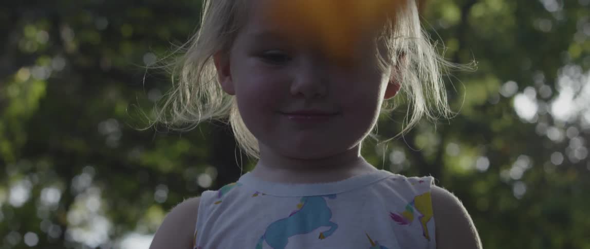 A little girls is watching leaves fall around her