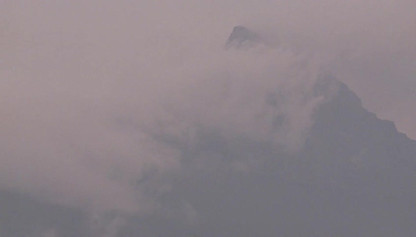 Fast moving clouds surround a mountain peak during a storm