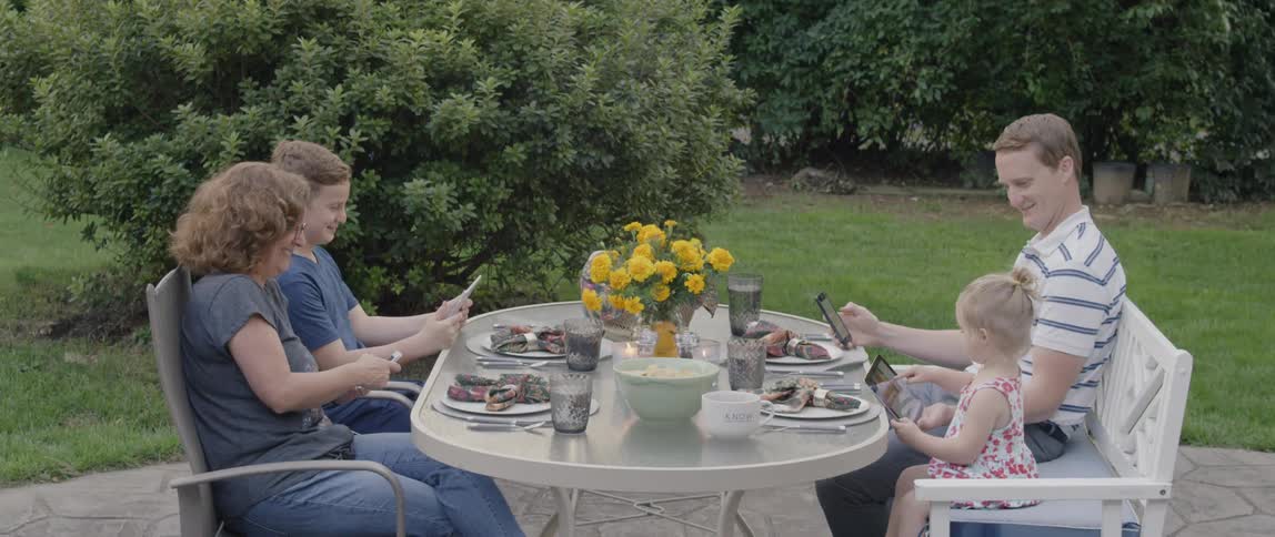 A family dines on an outdoor patio in their yard