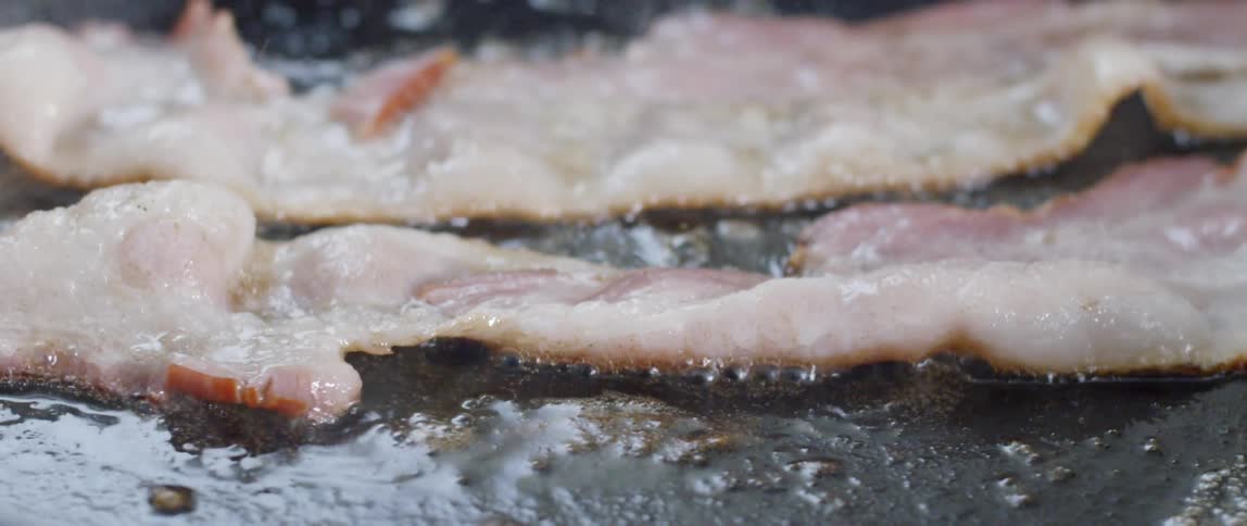 Bacon is sizzling as it cooks in a pan