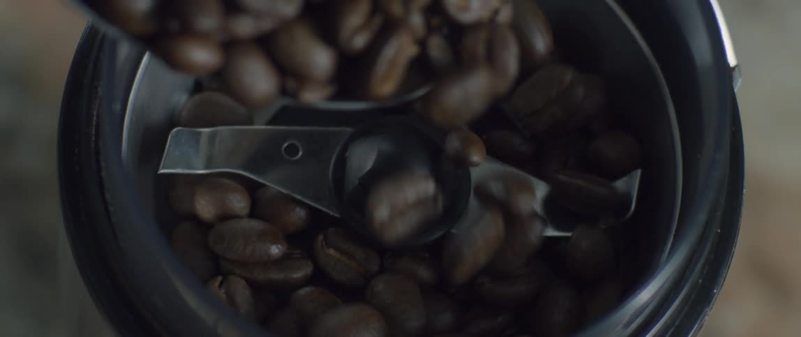 Coffee beans are poured into a grinder