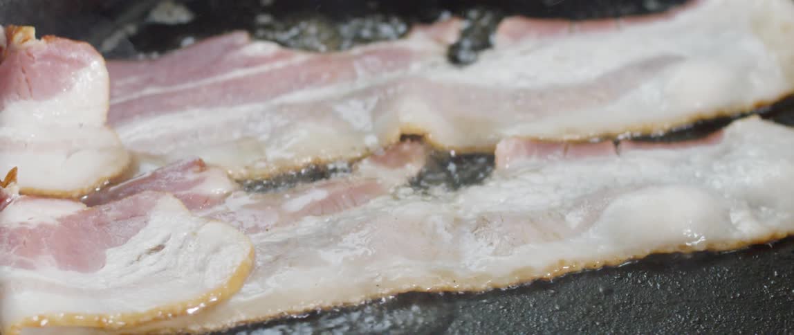 Close up of bacon frying in a skillet