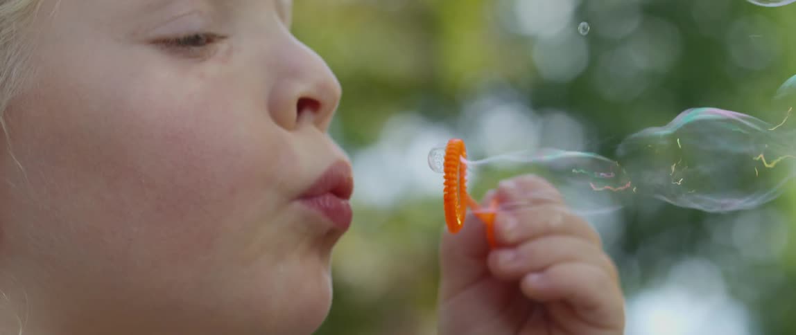Child blows bubbles on a sunny day