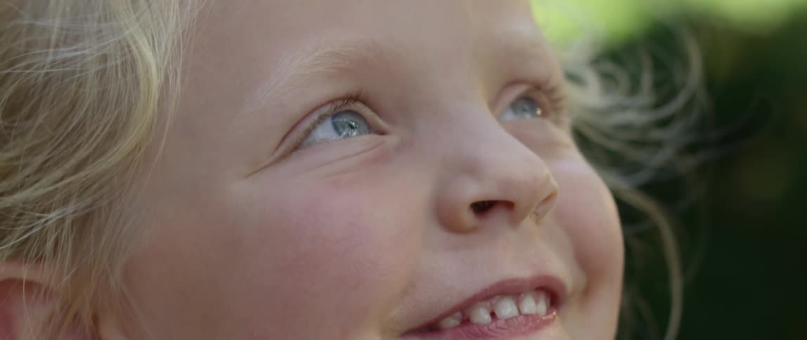 A blue eyed child outside in the day