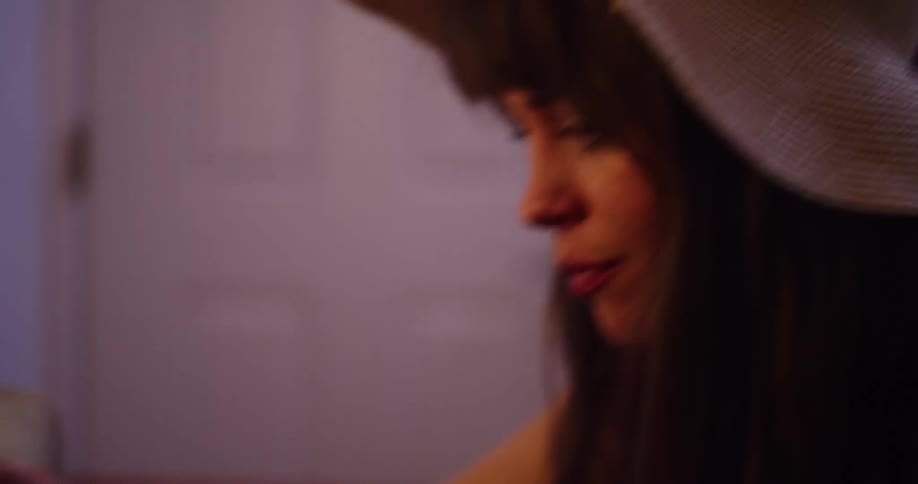 Close up slow motion shot of a woman in a sunhat placing a travel sticker on her vintage suitcase