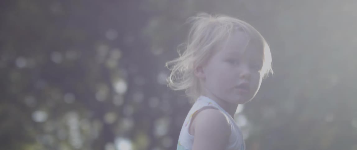 A toddler walks near trees on a sunny day