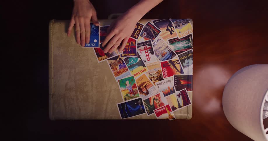 A traveler adds another destination sticker to their vintage suitcase, a collection of memories from their journeys
