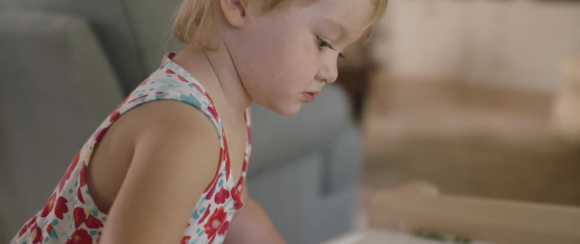 A young girl draws on a piece of paper with crayons