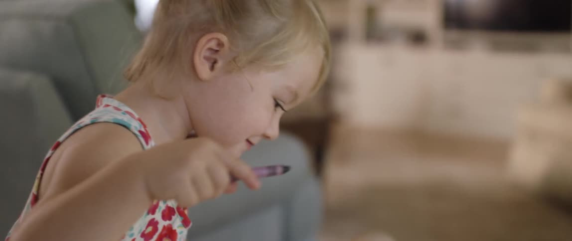 A young girl colors with a crayon