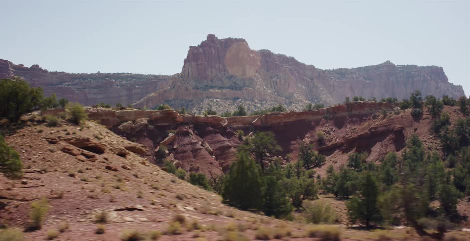 A scenic drive passes the majestic red rock formations and canyons of a desert landscape on a sunny day