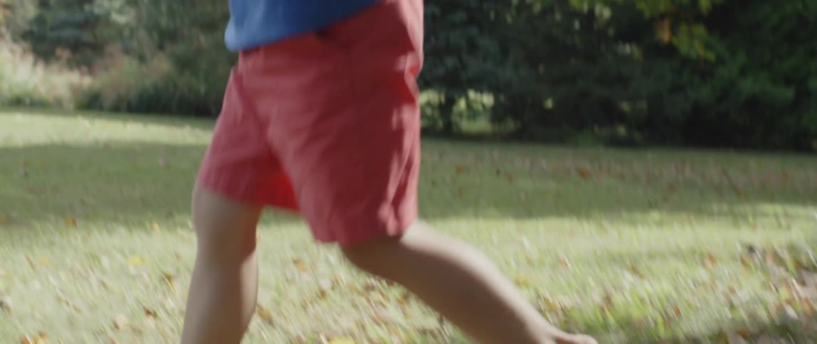 A boy runs barefoot across a lawn