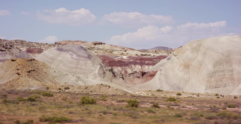 A picturesque landscape view of the colorful, stratified badlands of the Painted Desert from a moving vehicle