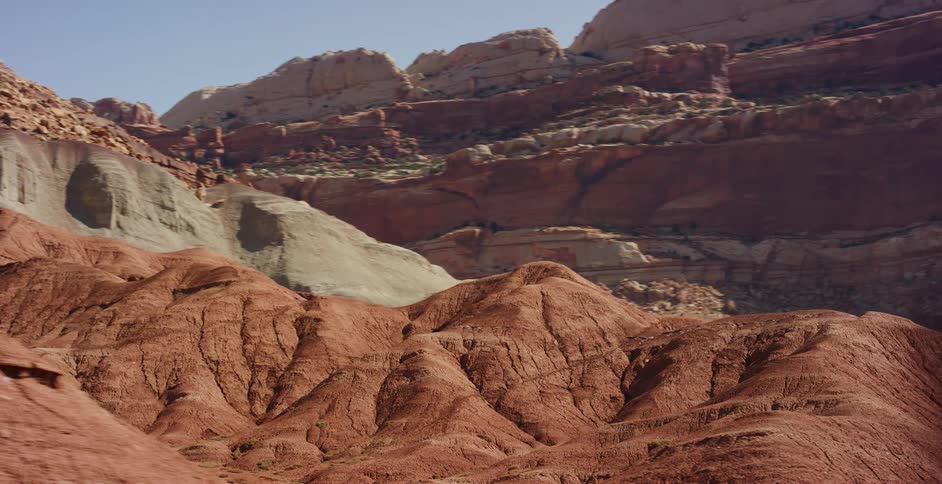Driving past the majestic and colorful layered rock formations of a desert canyon landscape on a bright sunny day