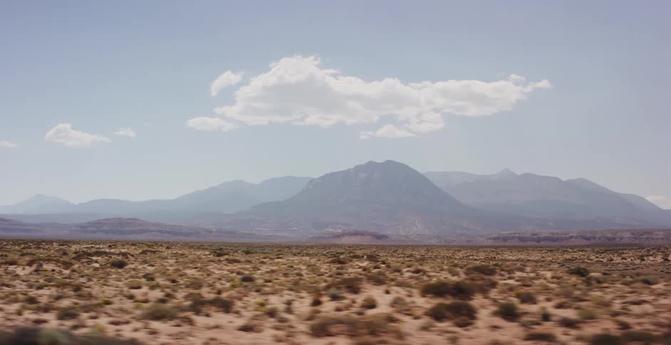A scenic drive through a vast desert landscape with majestic mountains visible on the horizon