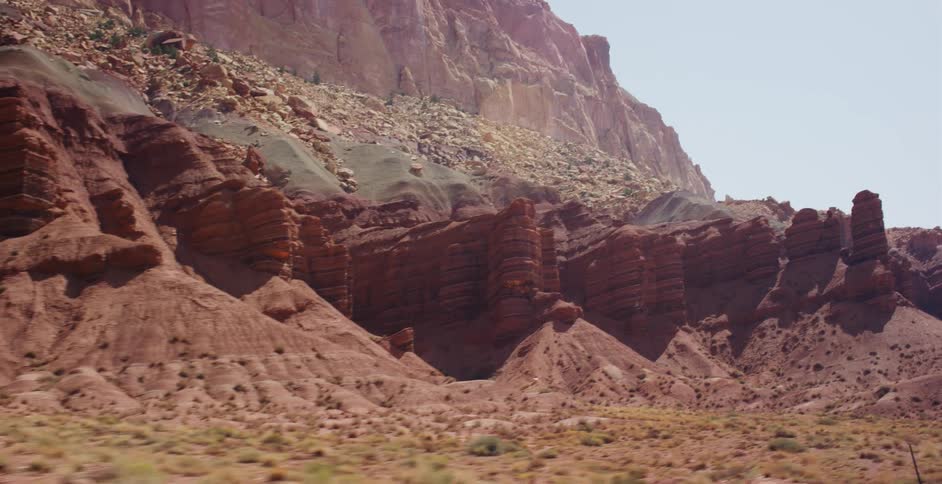 A scenic tracking shot reveals the vibrant red rock formations and canyons of a vast desert landscape