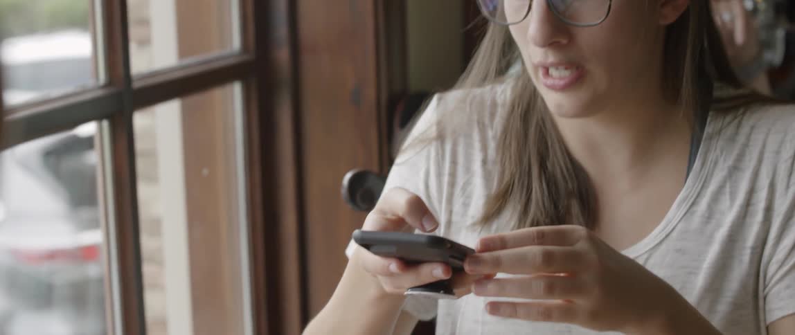Woman taking picture with cell phone of her food and drink in cafe