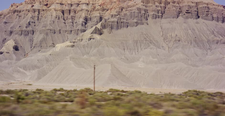 A majestic, flat-topped mountain with layered rock formations stands tall in the vast desert landscape of the American Southwest