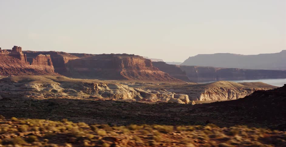 A scenic drive reveals the stunning red rock canyons and vast lake in the American Southwest desert during golden hour