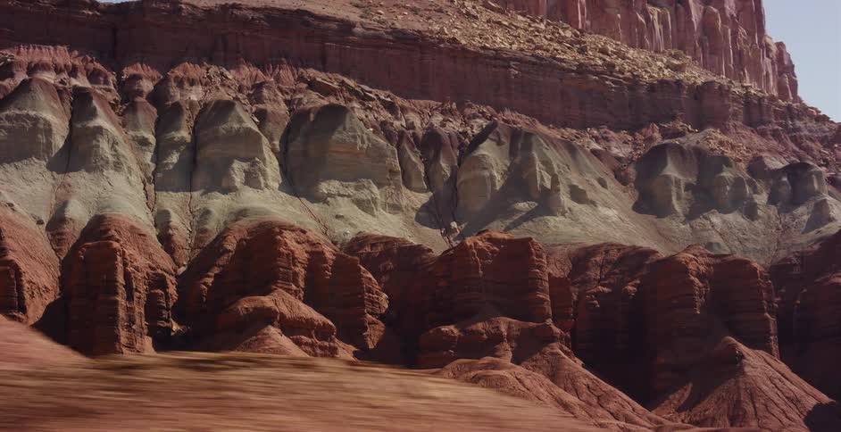 A sweeping aerial view reveals the majestic, multicolored layers of rock formations in a vast desert canyon