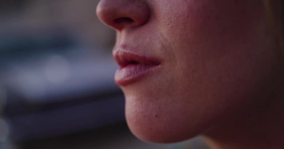 An intimate close-up shot of a woman's lips, chin, and nose with shallow depth of field
