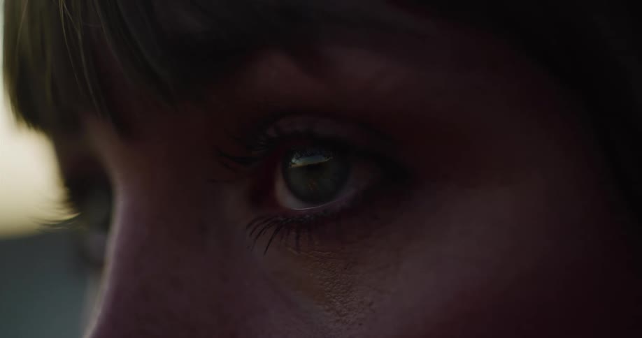 An intimate and dramatic close-up of a woman's eye looking thoughtfully as it catches the warm light of the golden hour