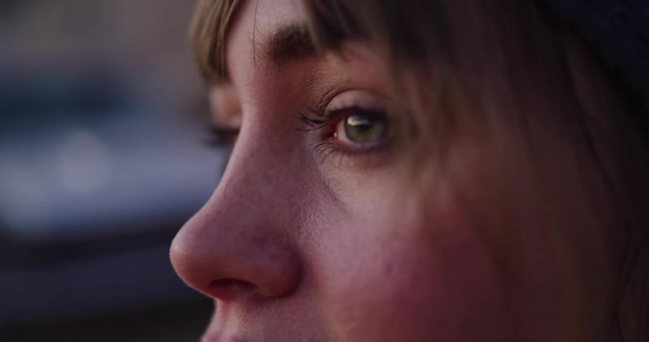 A thoughtful young woman's face is captured in an intimate slow-motion close-up as the camera focus racks from her mouth to her eye